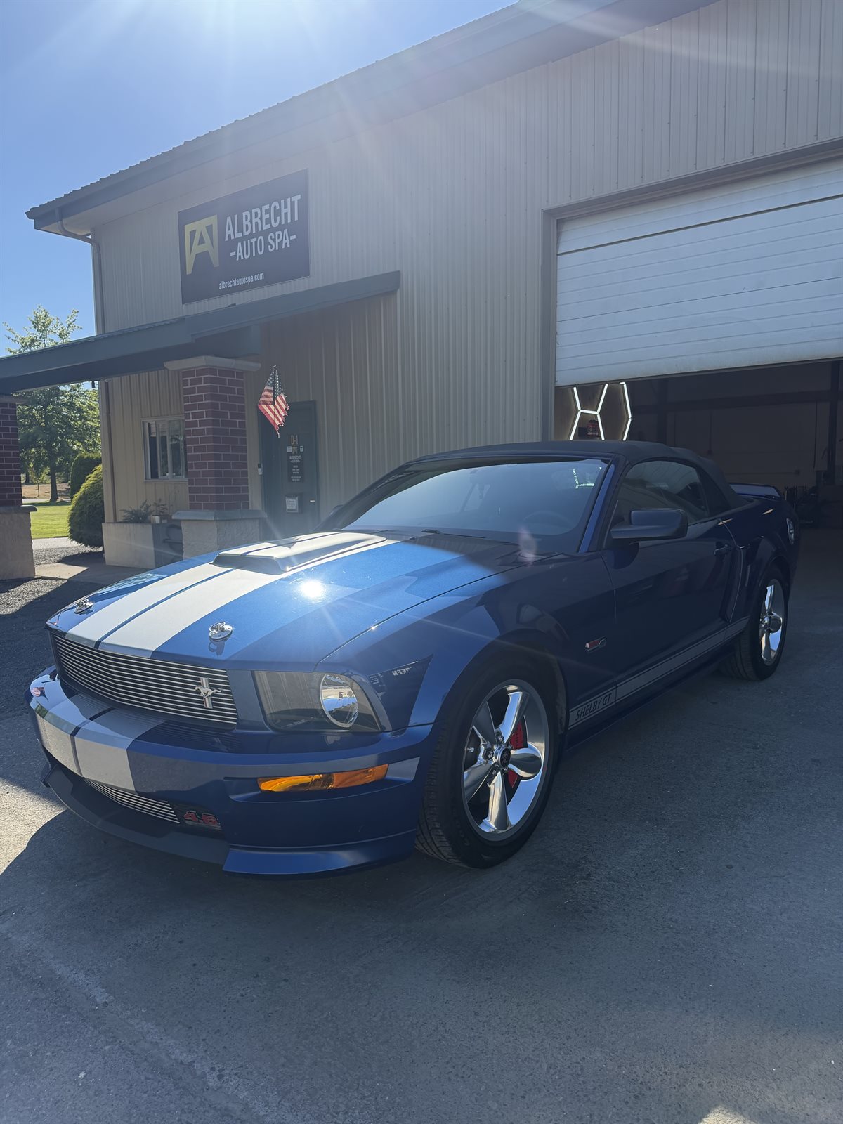 Blue Ford Mustang Shelby GT with white racing stripes in the Albrecht Auto Spa driveway