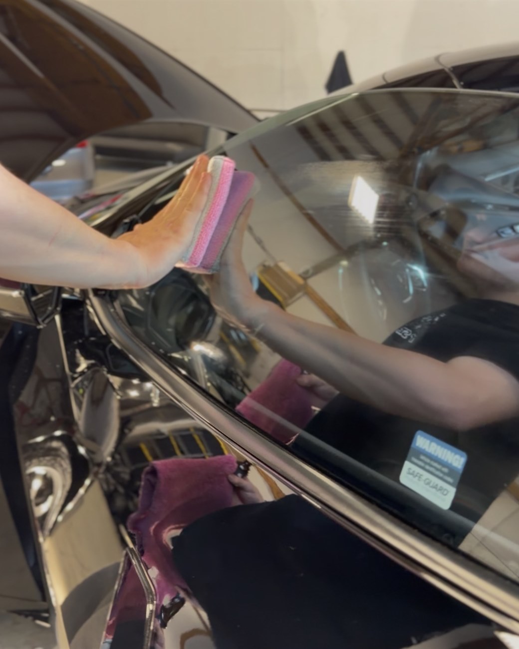 Ceramic coating applied to a vehicle's window glass with a pink applicator pad at Albrecht Auto Spa